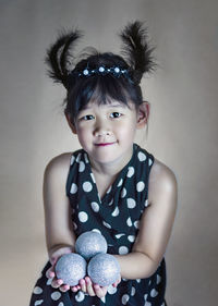 Portrait of cute girl standing against wall