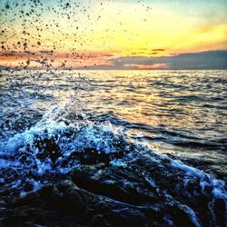 Waves splashing on rocks at sunset