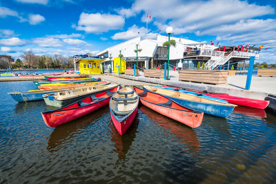 Boats moored at harbor against sky