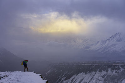 Rear view of man standing on mountain against sky during sunset