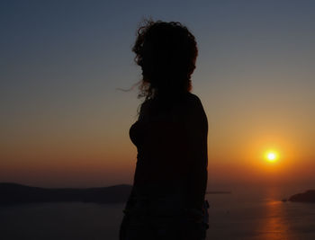 Side view of woman standing against sky during sunset