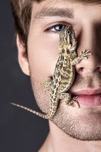 Close-up of lizard on man face