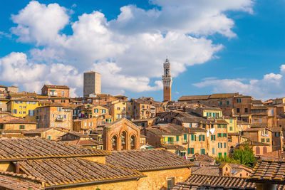 Buildings in town against cloudy sky