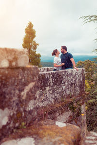 Couple embracing standing against sky