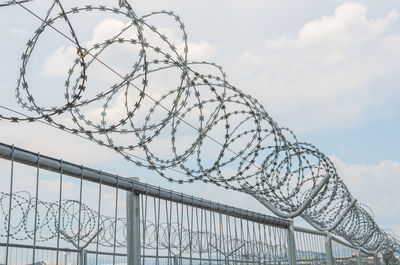 Low angle view of barbed wire fence against sky