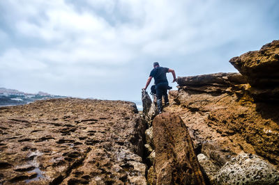 Rear view of men on rock against sky