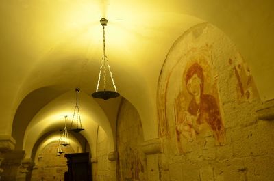 Low angle view of illuminated lamp hanging on ceiling of building