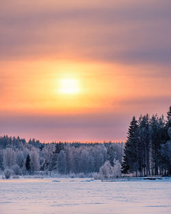 Scenic view of snow covered land against sky during sunset