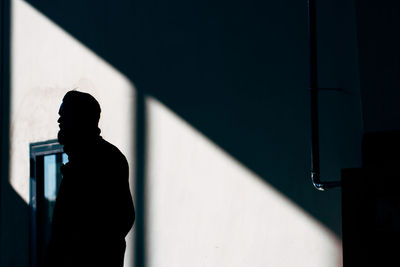 Silhouette hipster man standing against wall