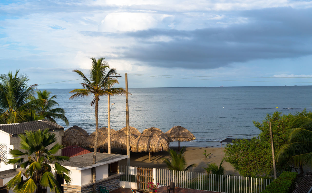 water, sea, sky, tropical climate, palm tree, vacation, cloud, nature, beach, tree, plant, ocean, land, beauty in nature, architecture, coast, horizon over water, travel destinations, scenics - nature, horizon, holiday, tranquility, trip, built structure, no people, travel, building exterior, outdoors, bay, day, coconut palm tree, building, tourism, tourist resort, tranquil scene, shore, idyllic, island, chair, resort, estate, house, tropics, environment