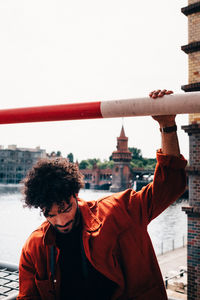 Man standing on cross in city against sky