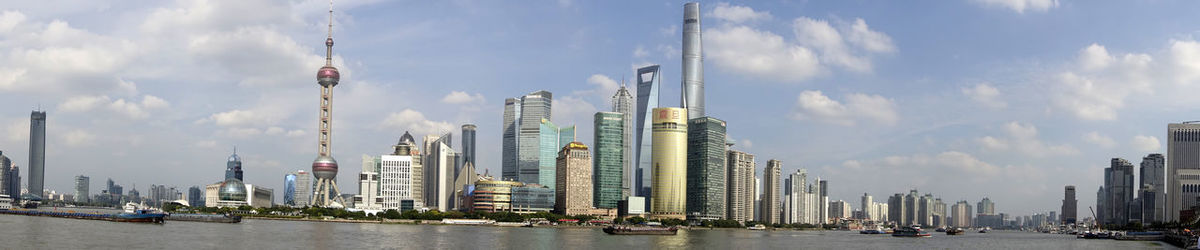 Panoramic view of skyscrapers against cloudy sky