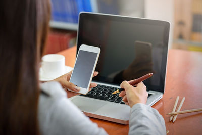 Midsection of woman using mobile phone on table