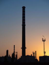 Industrial chimney seen in silhouette, pollution theme.