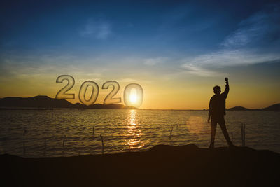 Silhouette person standing on beach against sky during sunset