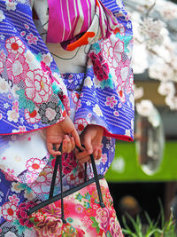 Midsection of woman wearing kimono holding bag