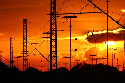 Low angle view of silhouette electricity pylon against sky during sunset