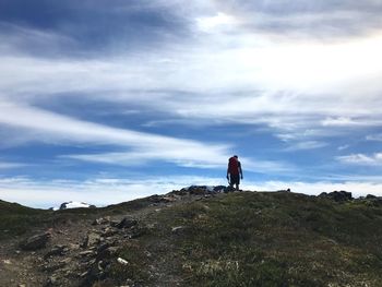 Rear view of man standing on mountain against sky