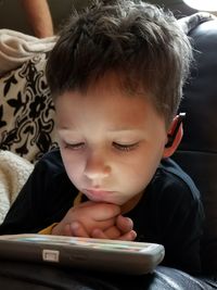 Close-up of boy using mobile phone at home