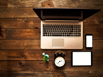 High angle view of clock and laptop on table