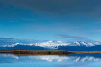 Scenic view of lake and snowcapped mountains against blue sky