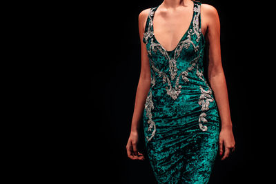 Green velvet evening dress on a female figure on a black background. feminine fashion clothes