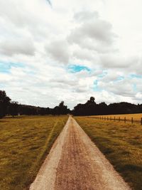 Road amidst field against sky