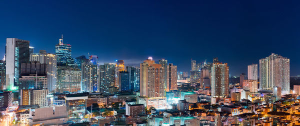 Illuminated buildings in city against blue sky