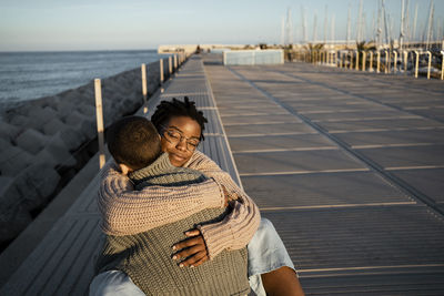 Female friends embracing each other while sitting on bench