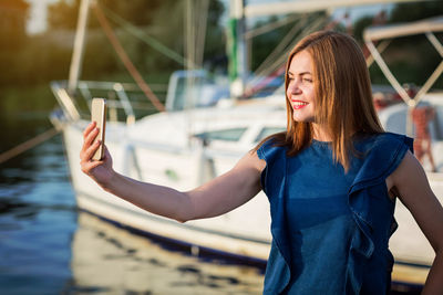 Portrait of smiling young woman standing against river