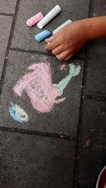 Cropped image of person with chalk drawing on walkway