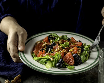 Midsection of person holding salad in plate