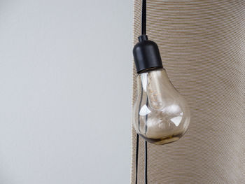 High angle view of light bulb hanging on table against white background