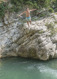 Full length of shirtless man standing on rock