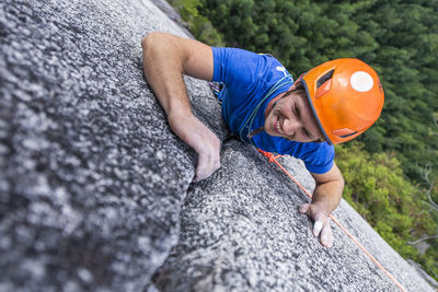 Climber looking up and laughing while rock climbing with helmet chief