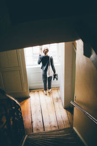 Woman looking through window at home