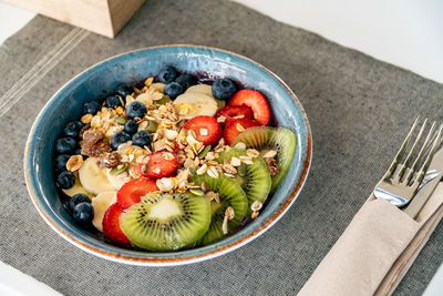 A bowl of acai ice cream topped with freshly sliced fruits and oats in a restaurant