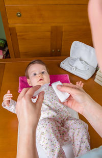Midsection of woman holding girl sitting at home