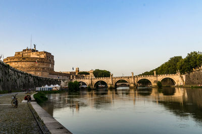 Arch bridge over river against blue sky during sunset