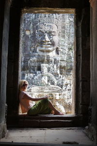 Side view of woman with statue on wall