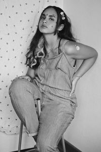 Young woman looking down while sitting against wall