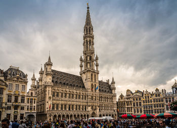 People at cathedral against cloudy sky