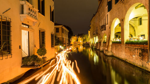 Light trails on street amidst buildings in city at night