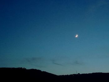 Silhouette landscape against blue sky at night