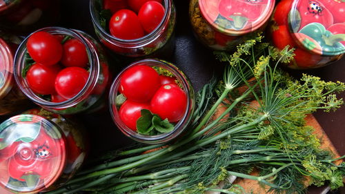 Close-up of tomatoes in glass jars by dill on table