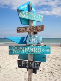 Information sign on beach against sky