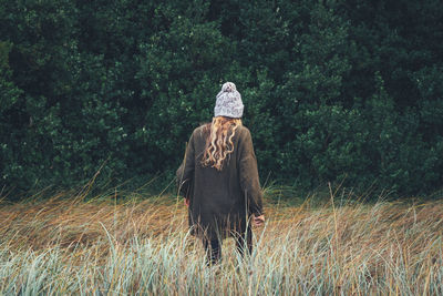 Rear view of woman walking against trees