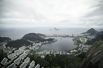 Aerial view of city at waterfront against cloudy sky