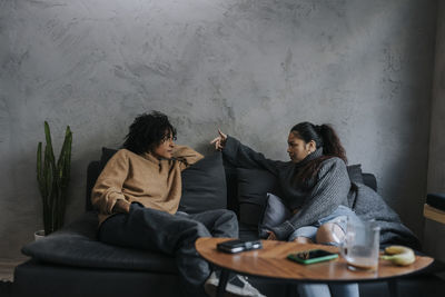 Young businesswoman planning strategy with female colleague while sitting on sofa at office