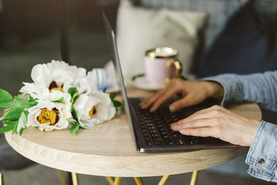 Midsection of woman using laptop on table